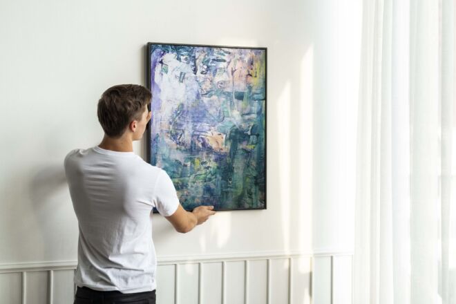 Vintage leaf painting frame psd being hung by a young man on a w